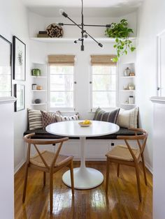 a white table and chairs in a room with wood floors, windows, and plants