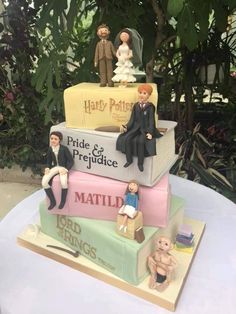 a cake made to look like three stacked suitcases with bride and groom figurines on top