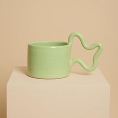 Handcrafted from stoneware clay, this mint green ceramic mug with distinctive wiggle handle is ideal for your morning coffee or afternoon tea. The quirky handle provides a playful aesthetic whilst also being ergonomic to hold. The Green Wiggle Mug will make a unique addition to your home and add a touch of joy to the everyday. Available in a range of colours, perfect for mixing and matching!  - Blue - Chartreuse - Mint Green - Orange - Pink 7cm high x 8cm wide Handmade in the UK. All pieces are entirely handmade in small batches from our East London studio. This means that some variations may occur, making each piece totally unique and special. Microwave and dishwasher safe, however I would recommend hand washing where possible. Funky Mug, Mug Handles, Morning Coffee Cups, British Gifts, Playful Aesthetic, Clay Mug, Pretty Mugs, Green Mugs, Clay Mugs