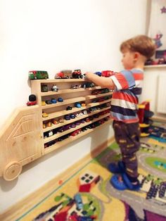 a young boy standing next to a wooden toy rack