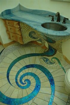 a bathroom with a sink, toilet and mosaic tile flooring on the ground in an artistic manner