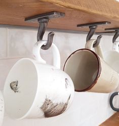 coffee mugs are hanging from hooks on the wall