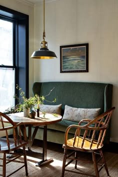 a living room with two chairs and a table in front of a large window that has a painting on the wall