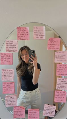 a woman taking a selfie in front of a mirror with sticky notes on it