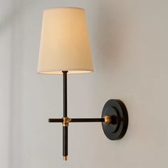 a wall light with a white shade on it's side and a black arm