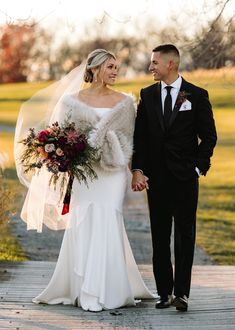 a bride and groom walking down a path holding hands