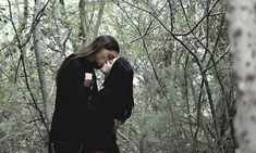 a woman standing in the woods with her hands on her face