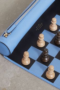 a blue purse sitting on top of a chess board with black and white pieces in it