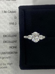 an engagement ring sits on top of a black velvet box with the price label below it