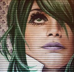 a painting of a woman with green hair and blue eyes is on the side of a garage door