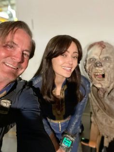 two people are posing for a photo in front of a fake zombie man and woman