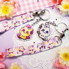 two keychains with cartoon characters on them sitting on a table next to flowers