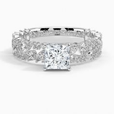 a princess cut diamond engagement ring with pave set diamonds on the band and side stones