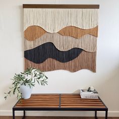 a wooden bench sitting in front of a wall hanging