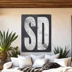 a white couch sitting in front of a black and white sign that says sd on it