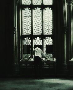 a person sitting on a bench in front of a large window with stained glass panes