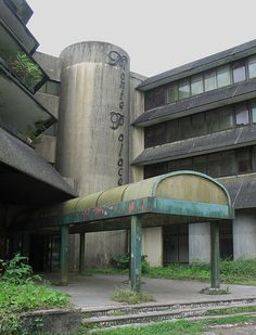 an abandoned building with graffiti on the side and green grass growing in front of it