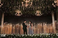 a bride and groom standing in front of candles