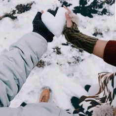 two people holding each other's hand in front of snow covered ground and rocks