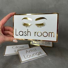 a person holding up a sign that says lashes room next to two cards with eyelashes on them