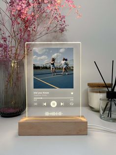 a wooden stand with an mp3 player on it next to some flowers and other items