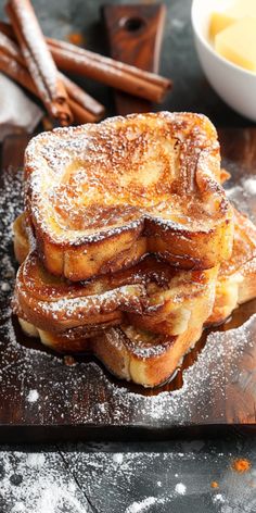 a stack of french toast sitting on top of a wooden cutting board covered in powdered sugar