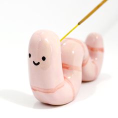 two pink snails with faces painted on them, one has a yellow stick in it's mouth