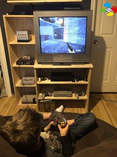 a young boy sitting in front of a tv holding a game controller