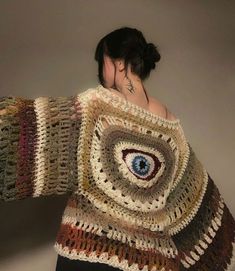 a woman wearing a crocheted sweater with an eye on it