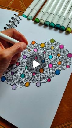 a person is drawing with markers and colored pencils