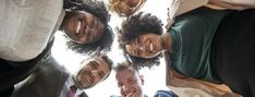 a group of people standing in a circle looking up at the camera with their heads together