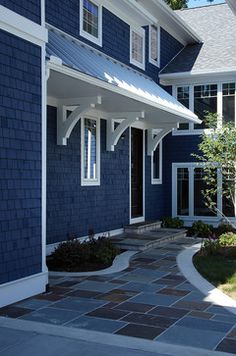 a blue house with white trim on the front door and windows, along with a brick walkway