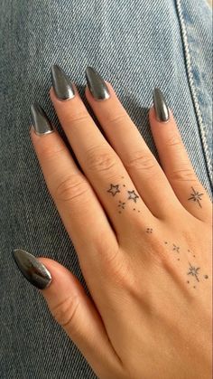 a woman's hand with silver nail polish and stars on her finger, while sitting down