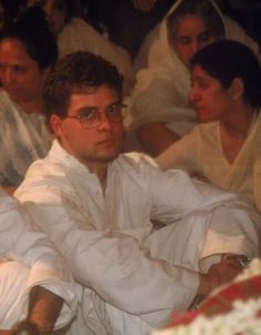 a group of people sitting next to each other wearing white robes and holding wine glasses