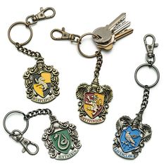 harry potter house keychains are shown in four different colors and styles, one is silver the other is black