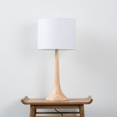 a wooden table with a lamp on top of it and a white lampshade