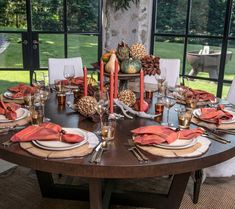 a dining room table set with place settings, candles and napkins for thanksgiving dinner