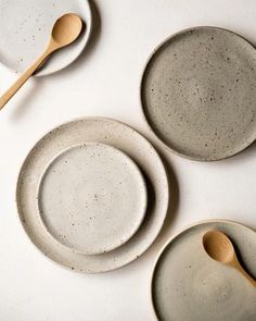 three plates and two spoons on a white table top with speckled glaze