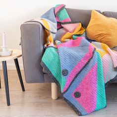 a couch with a blanket on top of it next to a table and two candles