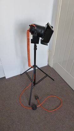 an orange cord is connected to a camera on a tripod in front of a door