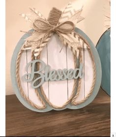 a wooden sign with the word, blessed on it and a bow hanging from it's center