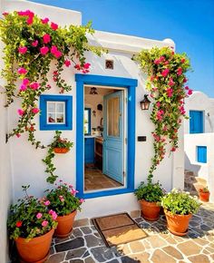 a blue and white house with potted flowers on the front door, in mykonia