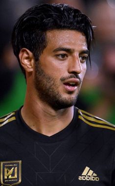 a close up of a soccer player wearing a black shirt and gold trimmings