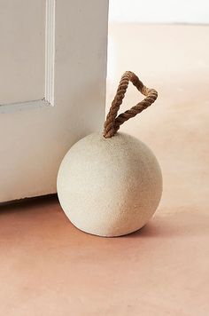 a white ball sitting next to a door with a rope on it's end