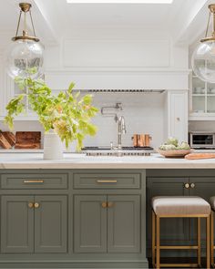 a kitchen with green cabinets and white counter tops, two hanging lights above the sink