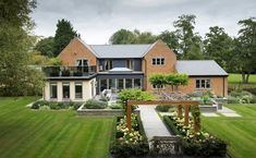 a large house sitting on top of a lush green field next to a garden filled with flowers