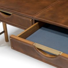 a brown leather desk with two drawers on each side and one drawer open to reveal a blue pad