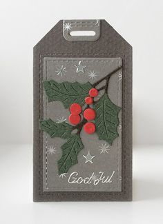 a christmas card with holly leaves and red berries on it, hanging from a gray hanger