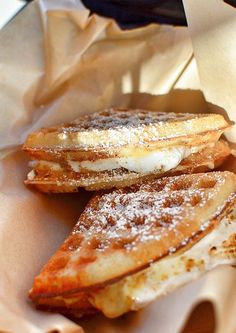 three pieces of french toast sitting on top of a paper bag covered in powdered sugar