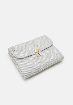 a white and blue striped bag with a gold button on the front, sitting on a white surface